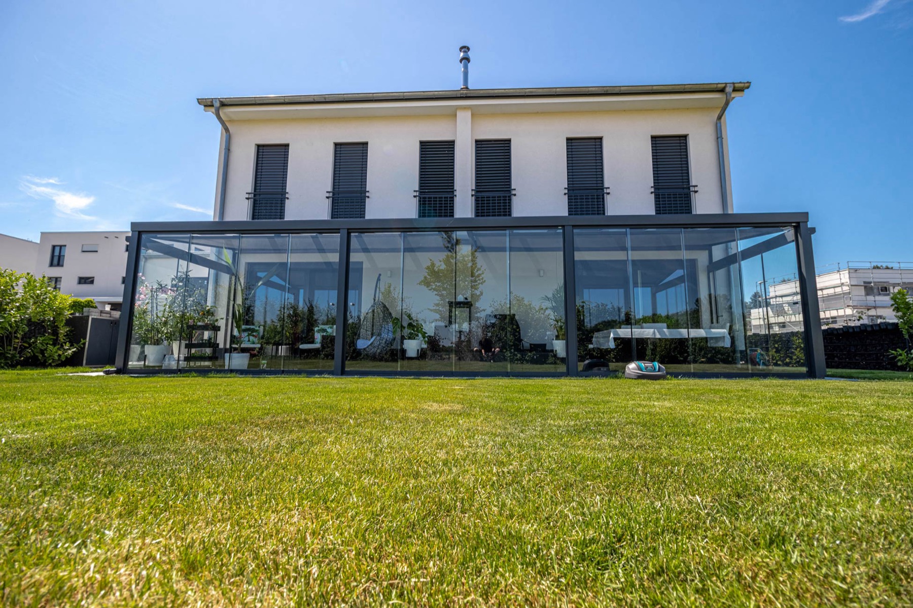 Großzügiger Sommergarten mit Glas-Schiebewänden am modernen Haus