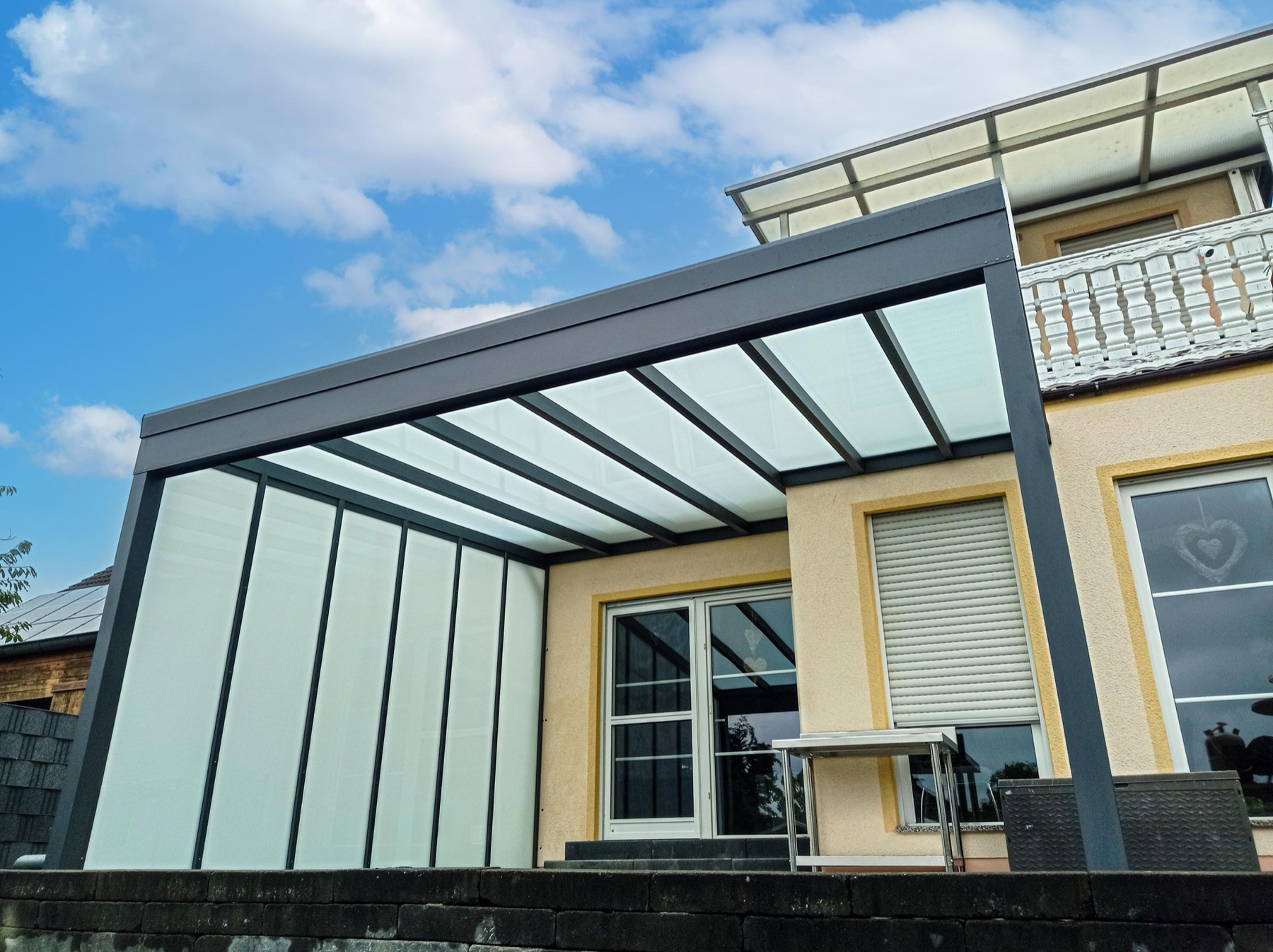 Alu-Terrassendach mit satiniertem Glasdach gegen blauen Himmel