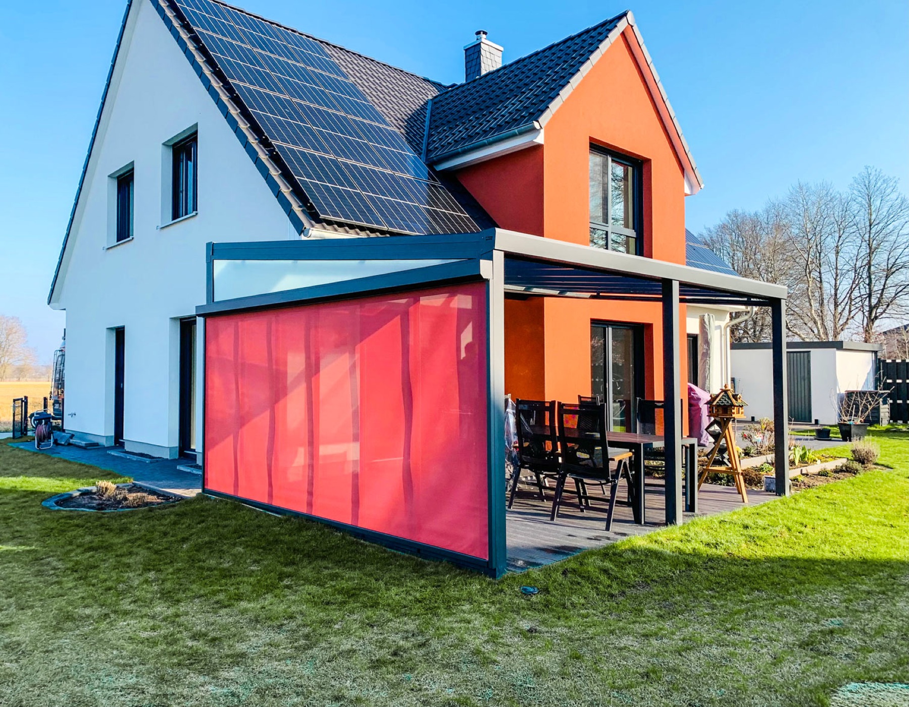 Terrassenüberdachung mit rotem Zip-Screen als Sonnenschutz